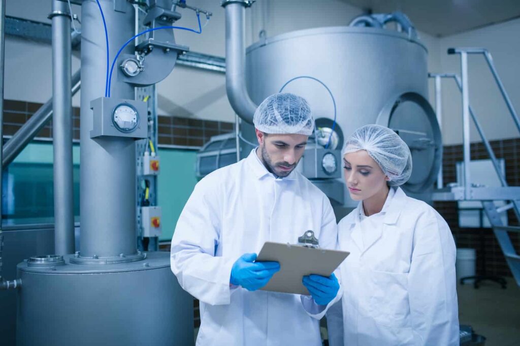 A production manager and her assistant evaluate the performance of used stainless steel tanks and equipment.