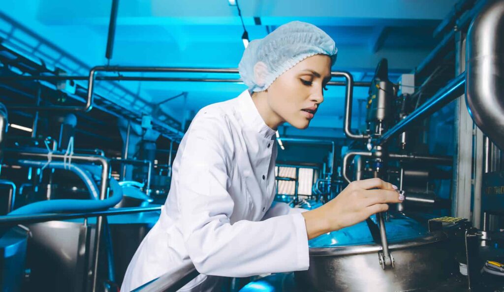 A worker checks her reconditioned milk processing equipment to ensure quality.