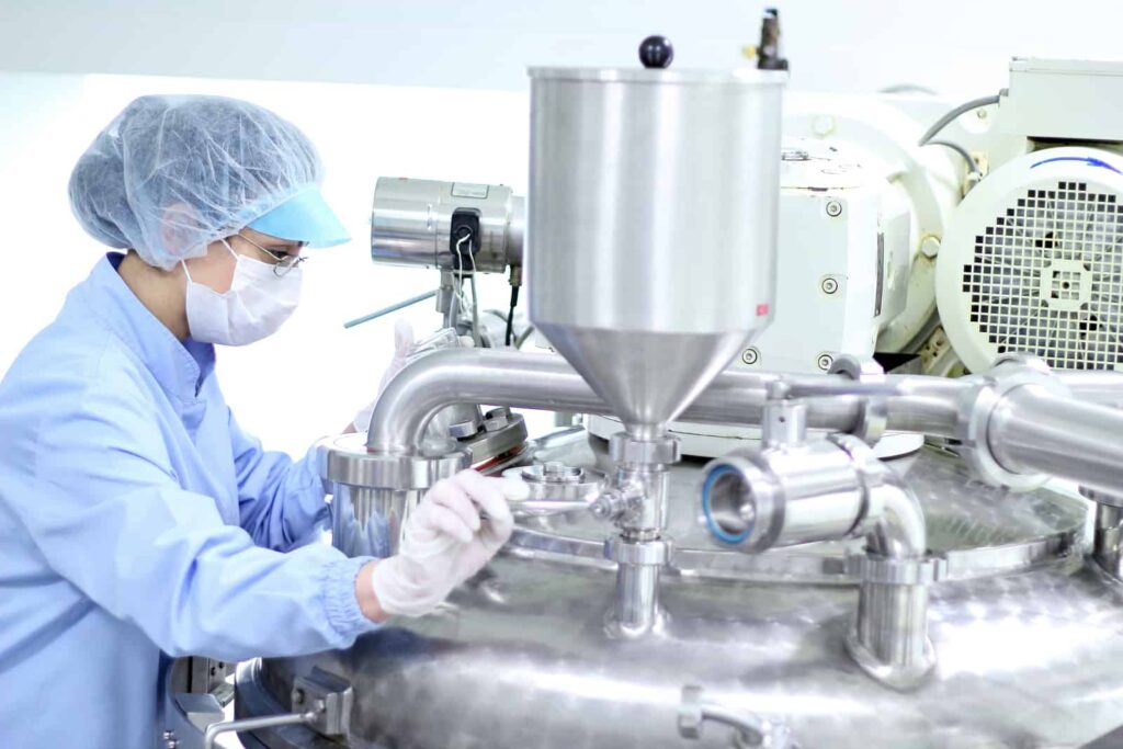 A pharmaceutical engineer works on a piece of equipment in her pharmaceutical processing plant.