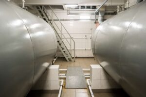 Horizontal steel storage tanks sitting on the first floor of a factory.