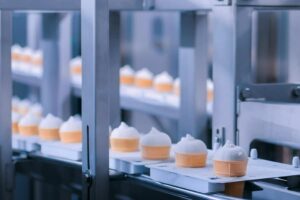 A conveyor belt filled with ice cream cones at a manufacturing facility.