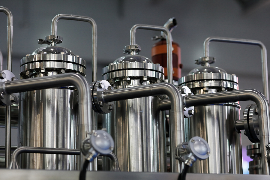 Three stainless steel tanks inside a manufacturing facility.